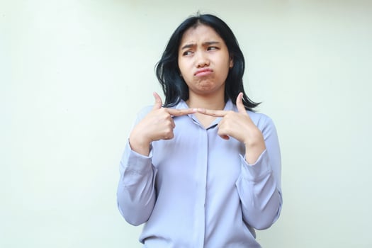 image of sad office girl, sulking asian woman dark haired entrepreneur looking away with stick finger feeling displeased offended wear formal purple shirt standing over isolated white background photo