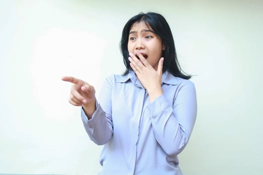 scared asian young business woman pointing looking away shocked covering her mouth wide open wear formal shirt standing over isolaed white background photo