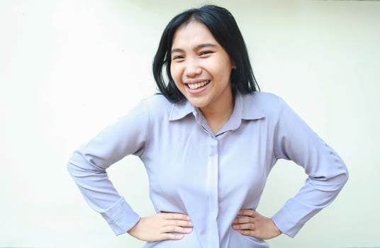 ecstatic asian business woman laughing at camera with hand on waist feeling confident with successful achievement wear formal office clothes standing over isolated white background photo