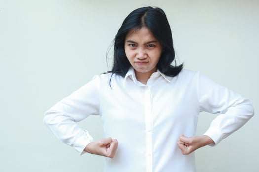 portrait of offended mad asian woman looking at camera with glare eye furious, lifting arm want to figt gesture, wearing white formal suit standing over isolated background photo