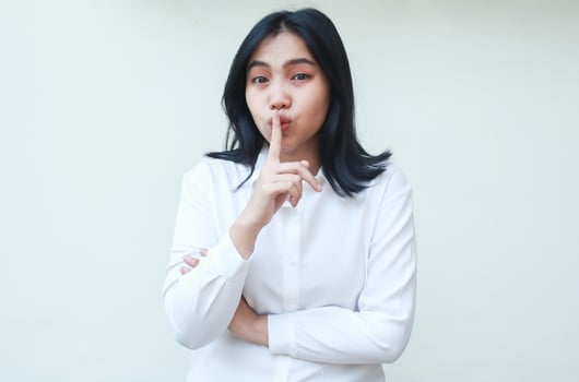happy calm beauty young asian business woman manager looking at camera with forefinger on lips mouth show silent gesture wearing white formal suit shirt, stop noise please photo