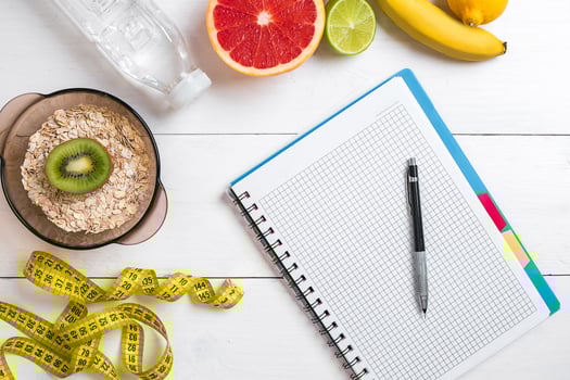 Healthy breakfast with oatmeal, fresh fruits and bottle of water with notebook on rustic wooden table. photo