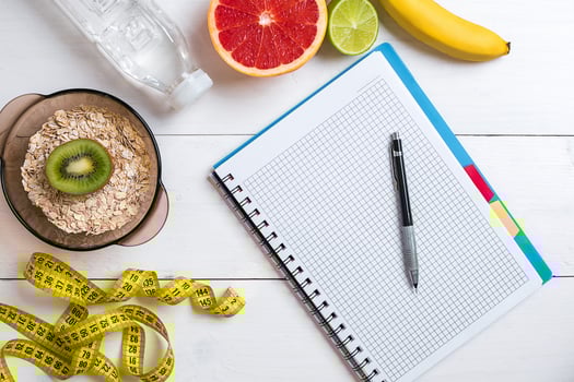 Fresh fruits with tape measure over white wooden background. Top view photo