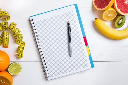 Fresh fruits with tape measure over white wooden background. Top view photo