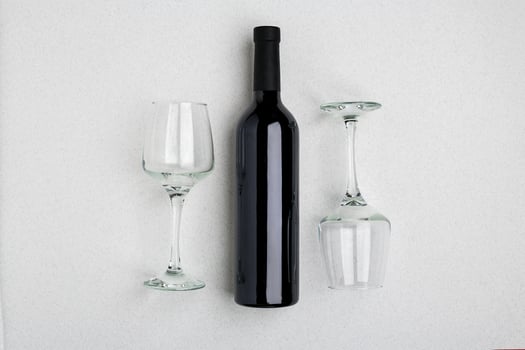 Overhead angled view of a large bottle of red wine, drinking glasses on white background photo