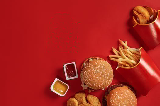 Two hamburgers and french fries, sauces on red background. Fast food. Top view. photo