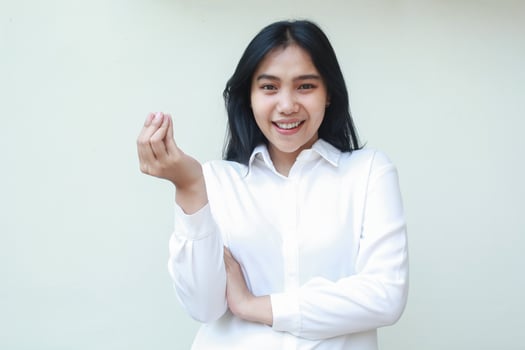 studio shot of smiling success asian woman secretary looking at camera showing satisfaction face expression with raising curled up finger and folding arms wearing white suit shirt standing isolated photo