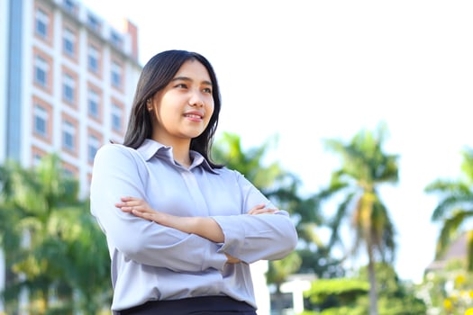 success asian businesswoman wear formal suit cross hand standing over urban building, agent insurance smiling confident looking away show optimistic expression photo
