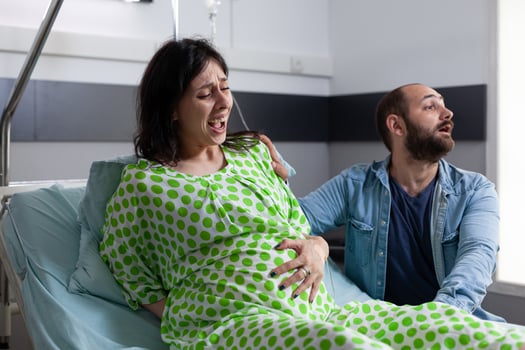 Panicked future father yelling for medic while pregnant woman having painful contractions in hospital ward. Patient with pregnancy getting into labor, asking for medical assistance giving birth photo