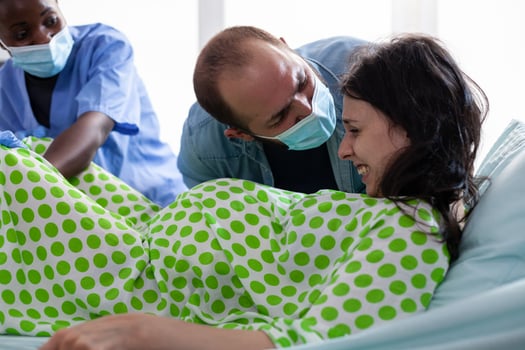 Father helping mother with painful contractions, offering moral support during child birth in hospital ward. Pregnant woman pushing and screaming during caesarean surgery. Parenthood concept photo