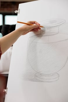 Woman student or art school drawing realistic vase in pencil, sketching on paper during lesson, learning pencil shading techniques. People learn to draw to train creativity in adulthood photo