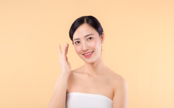 beauty asian young woman model with fresh glowing hydrated facial skin. girl person with natural makeup and healthy skin portrait isolated on beige studio background. spa treatment, skin care concept. photo