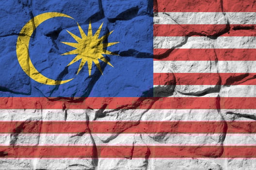 Malaysia flag depicted in paint colors on old stone wall closeup. Textured banner on rock wall background photo