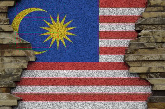 Malaysia flag depicted in paint colors on old stone wall closeup. Textured banner on rock wall background photo