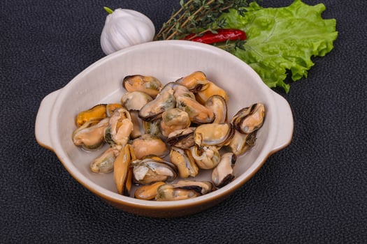 Pickled mussels in the bowl served pepper, garlic and salad photo