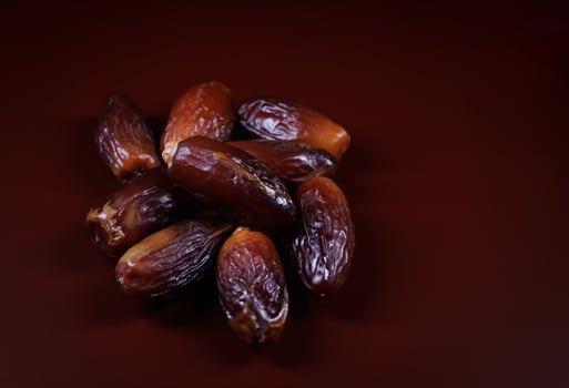 Several ripe dates on a dark red background. Delicious dates on red. photo