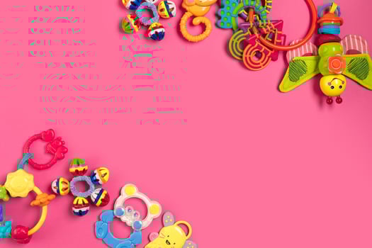 Children's rattle from plastic on a pink background. Top view photo