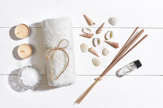 Spa set with sea salt, essential oil, soap and towel decorated with seashells on white wooden background photo