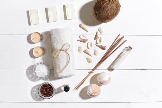Spa set with sea salt, essential oil, soap and towel decorated with seashells on white wooden background photo