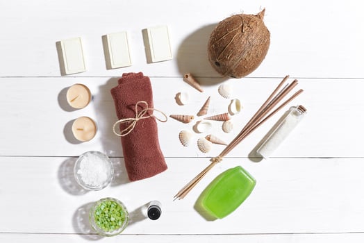 Spa set with sea salt, essential oil, soap and towel decorated with seashells on white wooden background photo