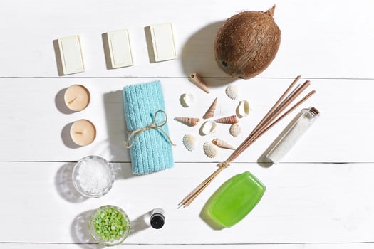 Spa set with sea salt, essential oil, soap and towel decorated with seashells on white wooden background photo