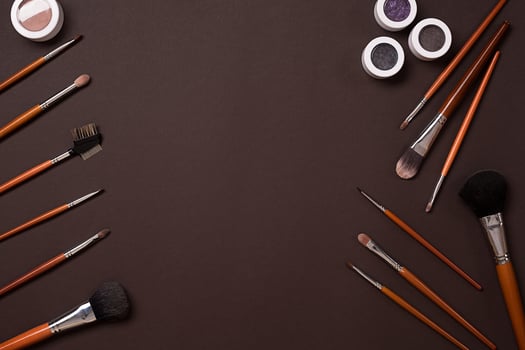 Various cosmetics and brushes on brown background photo