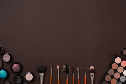 Various cosmetics and brushes on brown background photo