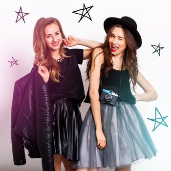 fashion portrait of two elegant stylish  women wearing a leather  skirt and black hat , holding  retro camera.  Posing against white background. photo