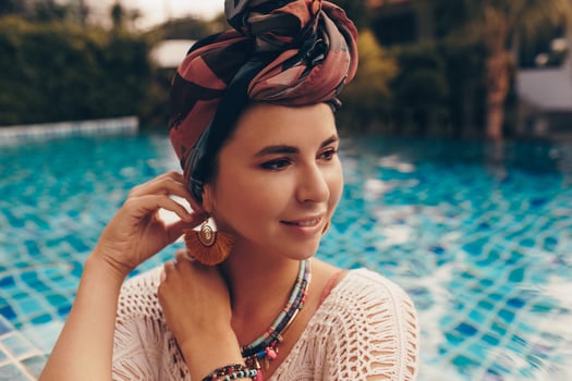 Woman with bright make up in bohemian outfit, turban, ethnic earrings, necklace and bracelets posing in swimming pool. photo