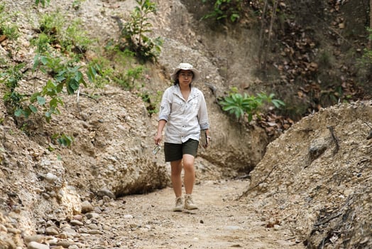 Female geologist holding magnifying glass and laptop working examining rock, soil, sand in nature. Archaeologists explore the field. Environmental and ecology research. photo