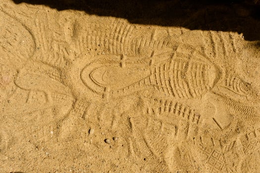 View of a shoe footprint in the sand. Texture of yellow sand with traces of different shoes. photo