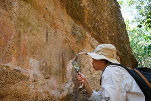 Female geologist using a magnifying glass examines nature, analyzing rocks or pebbles. Researchers collect samples of biological materials. Environmental and ecology research. photo