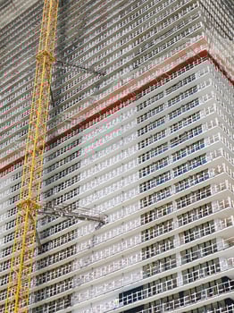 Modern unfinished skyscraper witha yellow lifting crane attached. photo
