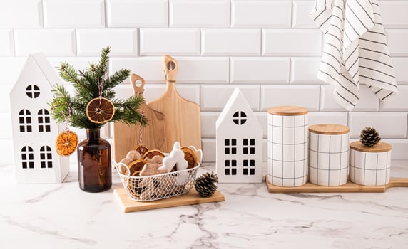 Chic kitchen background in light colors with trendy decorations for New Year. White houses, a vase with spruce branches and dried orange slices. photo