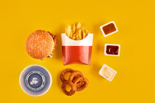 Fast food dish top view. Meat burger, potato chips and wedges. Take away composition. French fries, hamburger, mayonnaise and ketchup sauces on yellow background. photo