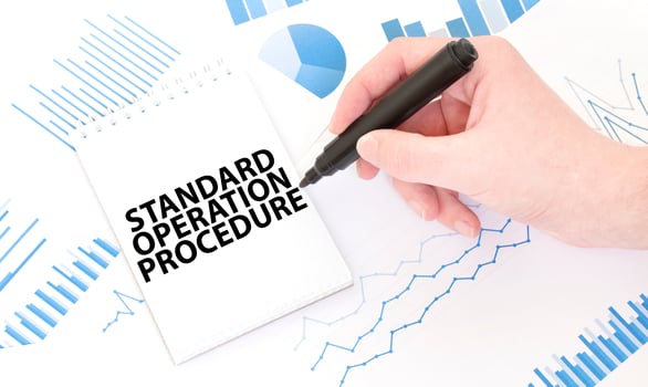 Businessman holding a black marker, notepad with text STANDARD OPERATION PROCEDURE ,business concept photo