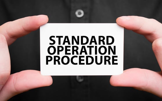Businessman holding a card with text STANDARD OPERATION PROCEDURE, business concept photo