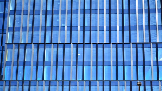 Glass building with transparent facade of the building and blue sky. Structural glass wall reflecting blue sky. Abstract modern architecture fragment. Contemporary architectural background. photo