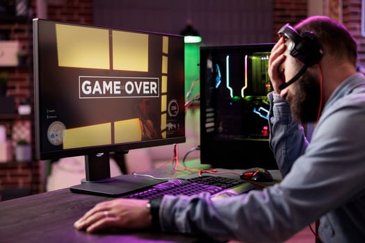 Gamer losing intense singleplayer spaceship arcade racing videogame, seeing game over screen on capable gaming computer system at home. Man being upset after being defeated on difficult game level photo