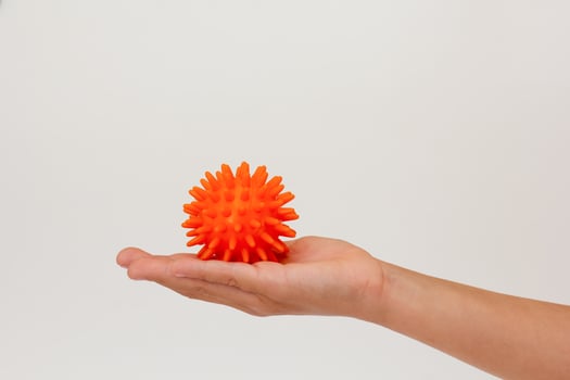 Child hand holding orange spiky ball for massage photo