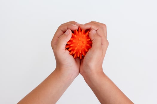 Child hands holding orange spiky ball for massage photo