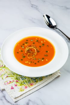 top view of pumpkin cream soup with pieces of meat in a white plate photo