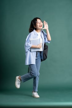 Portrait of a beautiful Asian student on a green background photo