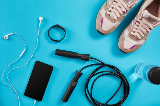 Flat lay shot of Sport equipment. Sneakers, jump rope, earphones and phone on blue background. photo