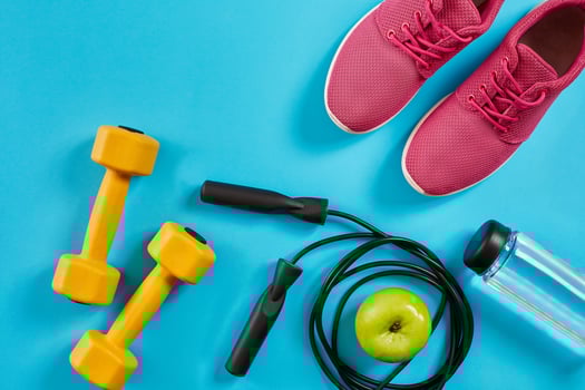 Flat lay of female sport equipments, jump rope, bottle of water and pink sneakers on blue background photo