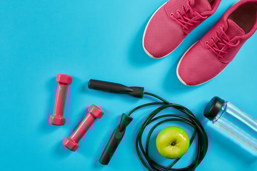 Flat lay of female sport equipments, jump rope, bottle of water and pink sneakers on blue background photo