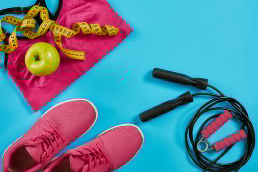 Flat lay of female sport equipments in pink color with jump rope and sneakers on blue background photo