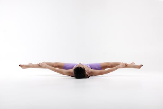 Woman doing stretching in a purple sports suit on a white background photo