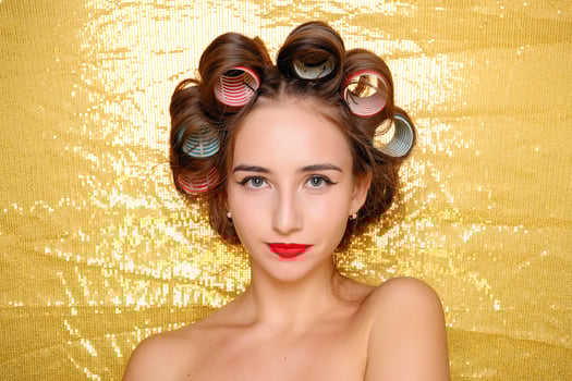 Beautiful girl in hair curlers isolated on gold photo