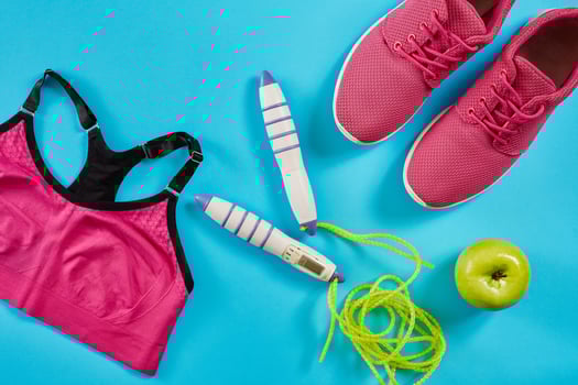 Flat lay of female sport equipments in pink color with jump rope and sneakers on blue background photo